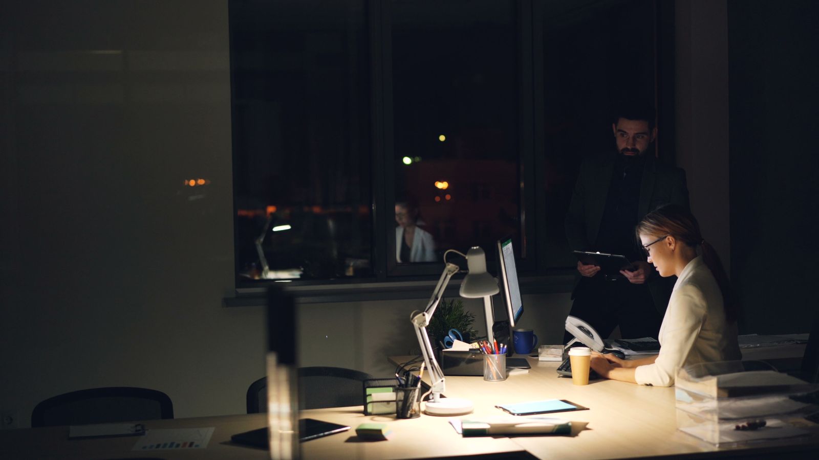 Dos profesionales revisando trabajo en una oficina de noche